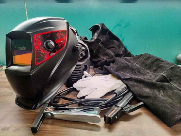 Sveiseapparat med hjelm, hansker og forkle