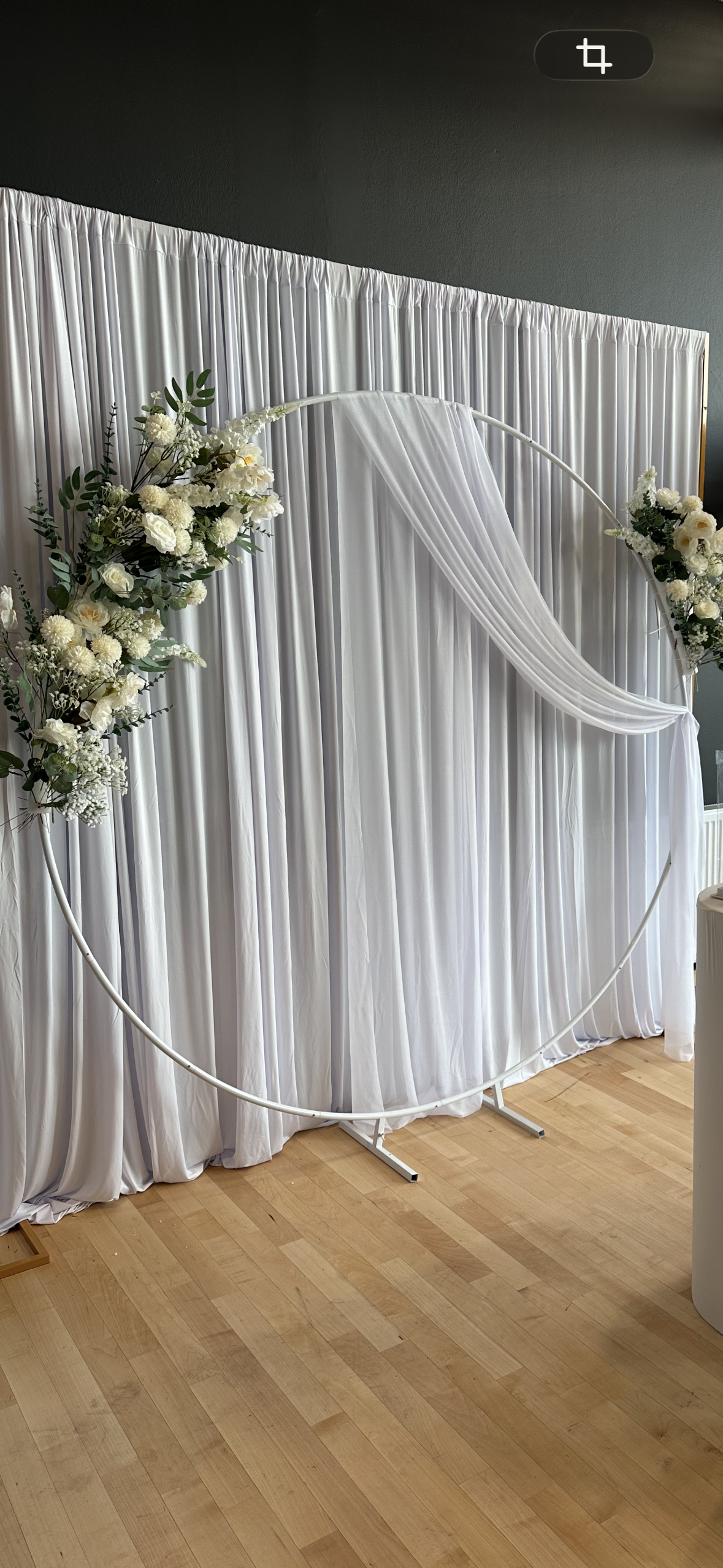 Rund vit båge med vitt tyg och blommor