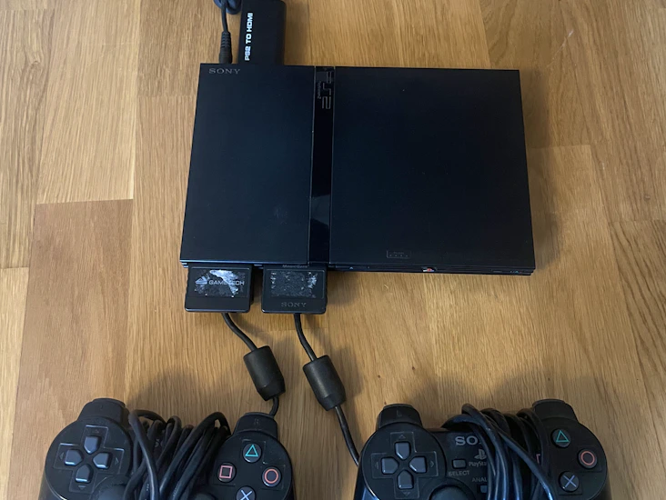 Ps2 med två kontroller och massor av spel.