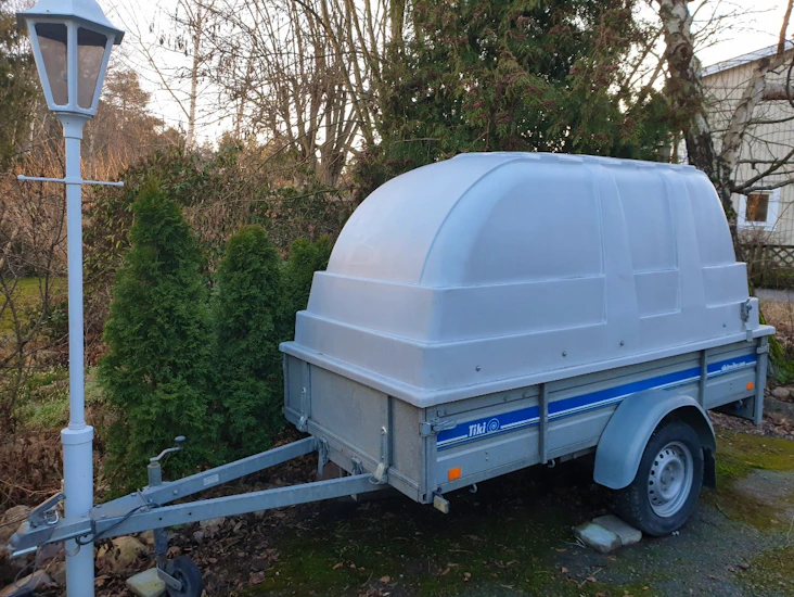 Täckt släp med låsbar kåpa och tippfunktion.